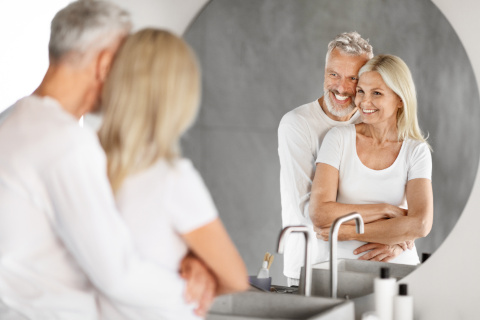 Elderly couple smiling inside their newly installed accessible shower room in Chichester, reflecting comfort and satisfaction.