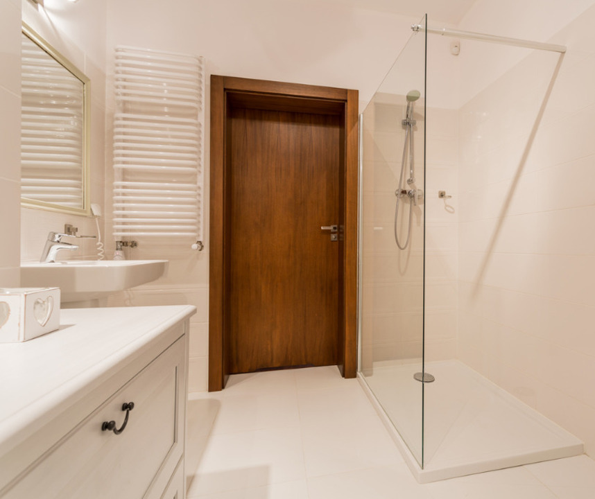 Spacious easy-access shower room with a sleek, modern design, featuring a no-threshold entry, safety handrails, and a stylish shower screen for comfortable and independent bathing.